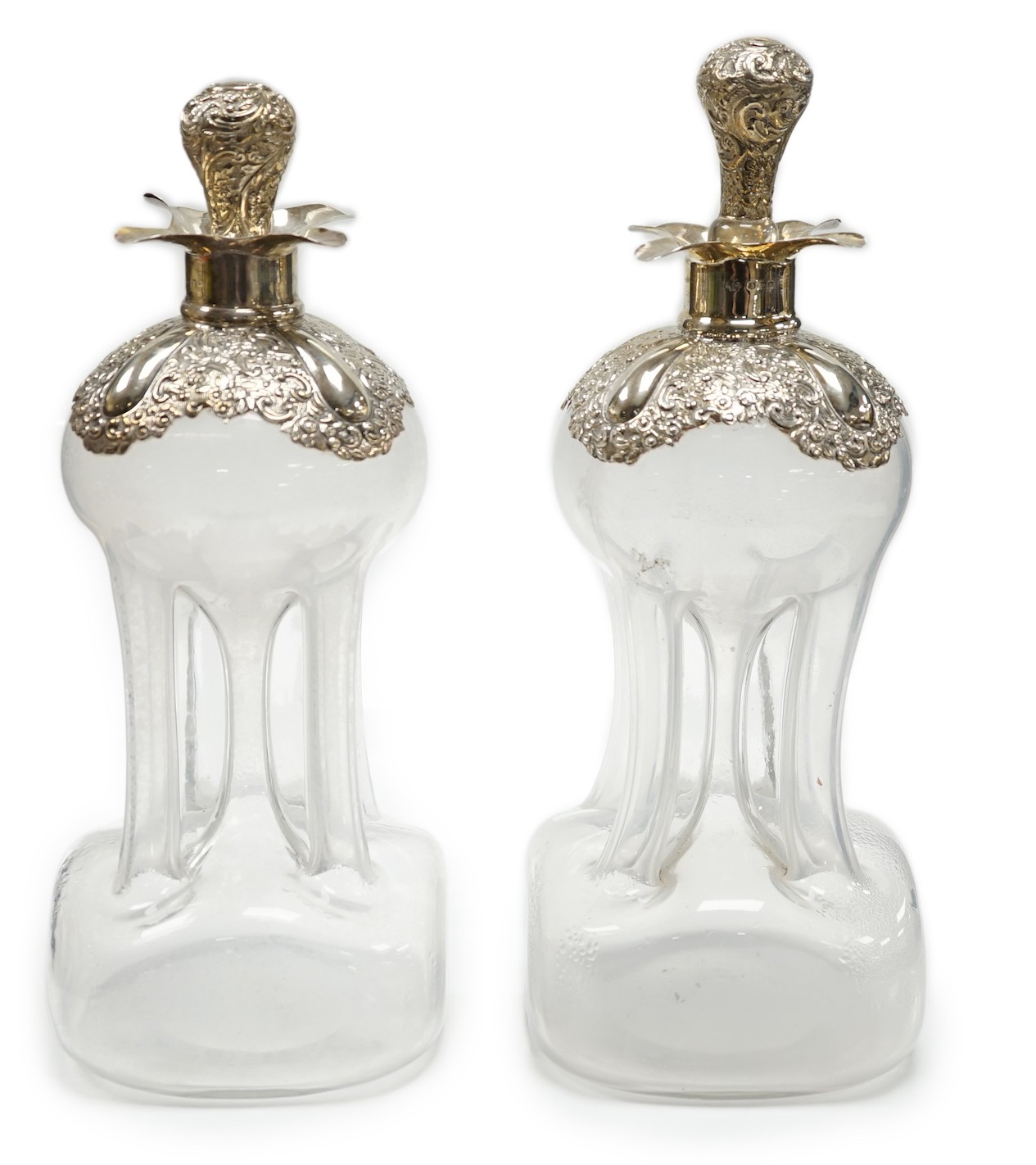 A pair of Edwardian silver mounted glass hour glass shaped decanters, William Hutton & Sons, Birmingham, 1906/7, with associated stoppers, height 23.9cm.